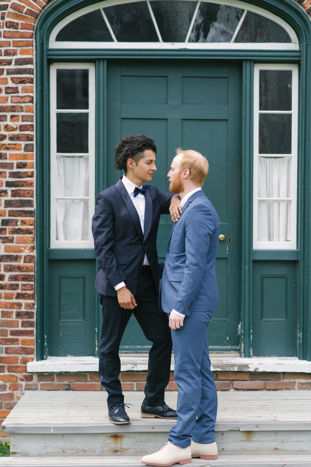 two men in suits looking at each other lovingly